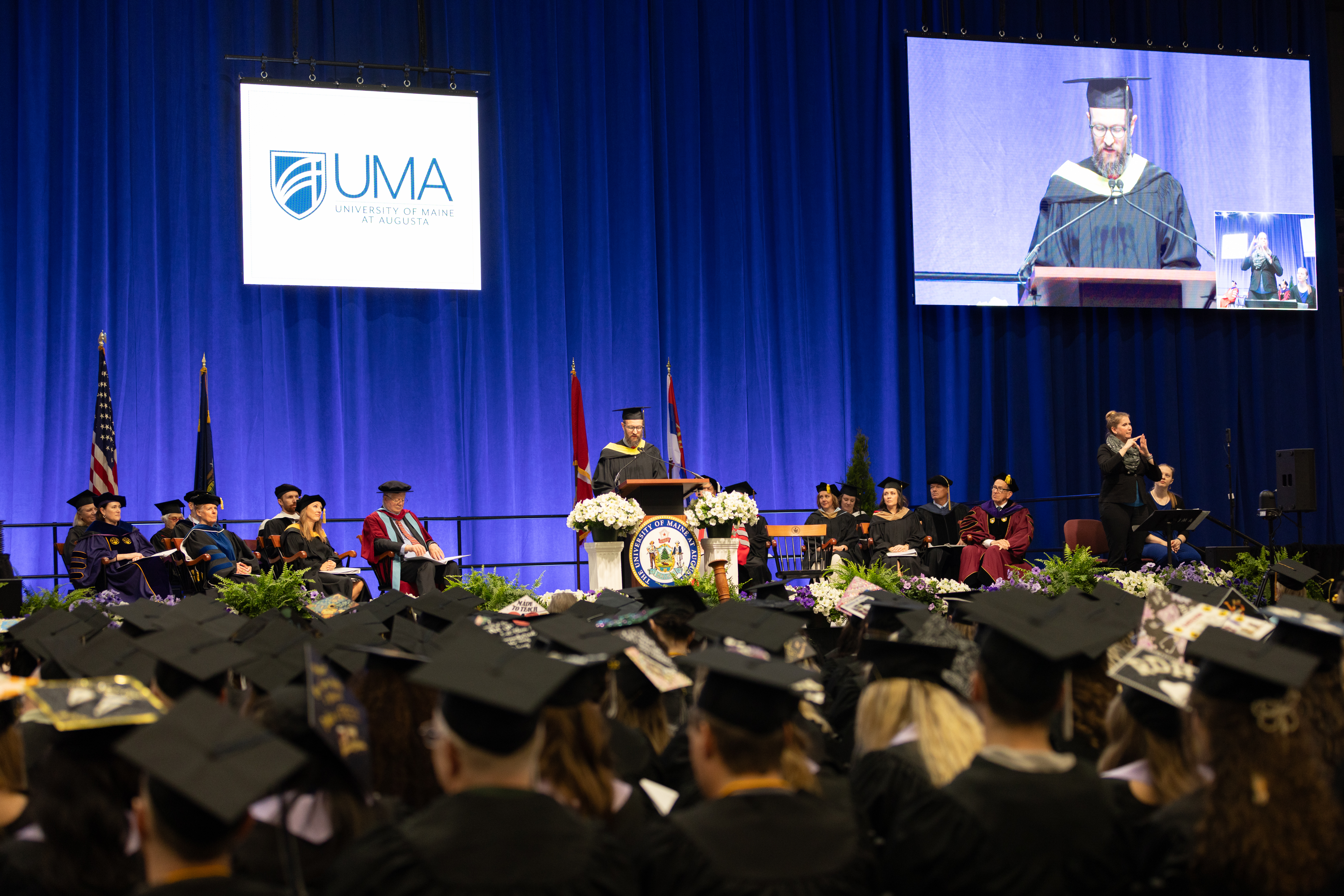Graduating student in cap and gown sitting before receiving diplomas